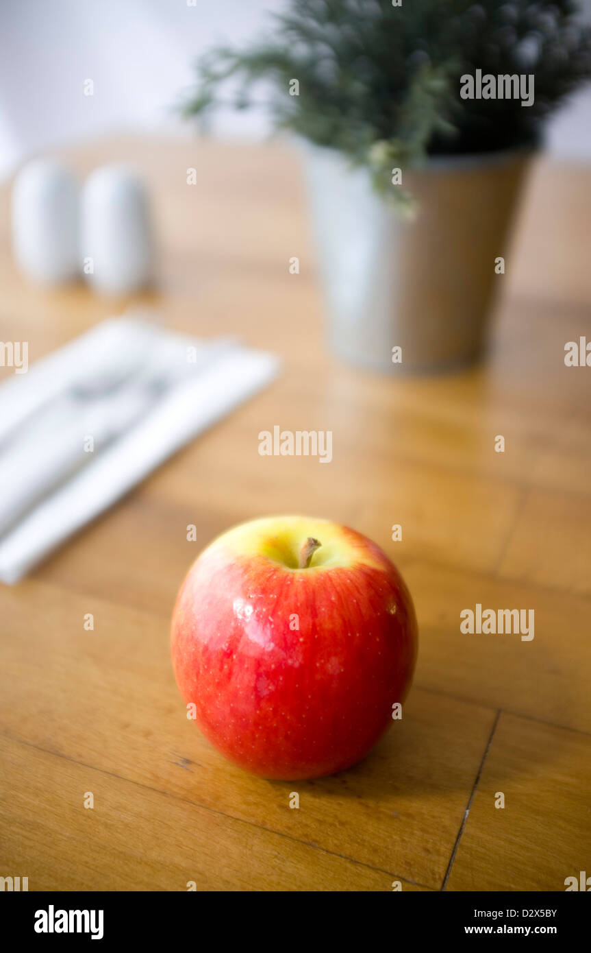 Shiny glossy red apple on a table in a restaurant or dining setting Stock Photo