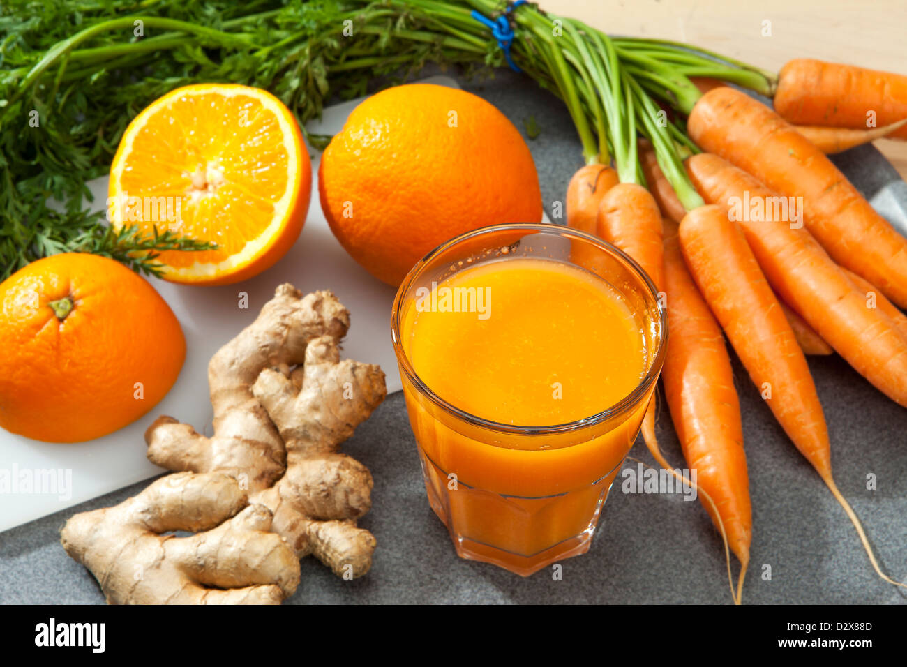 Glass of fruit juice with orange, carrots and ginger on a cutting board Stock Photo