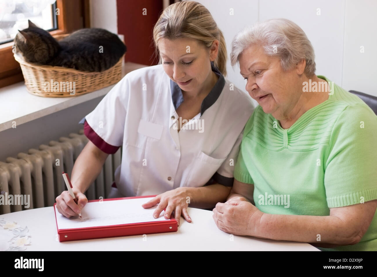 blond nurse visiting a senior patient at home Stock Photo