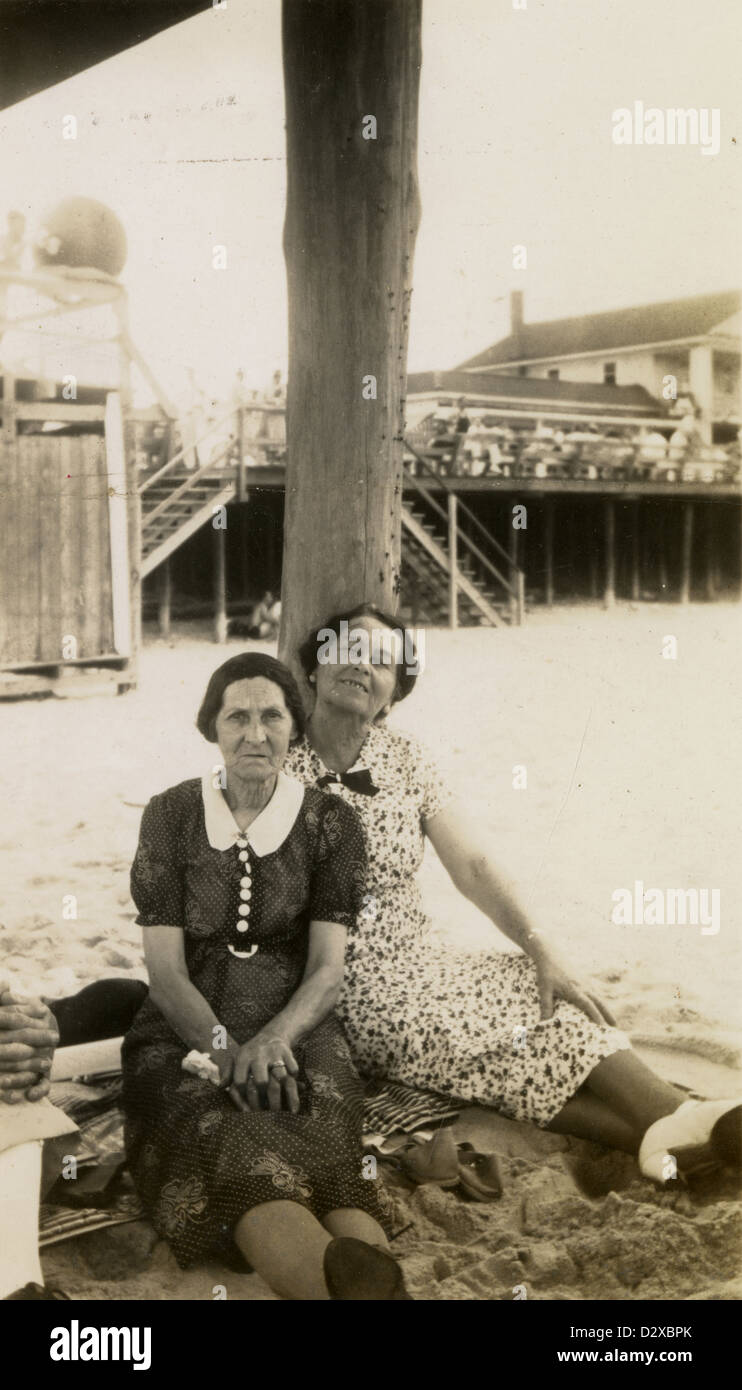 Circa 1900s photograph, two elderly women, perhaps sisters, beneath a pier having a beach picnic. Stock Photo