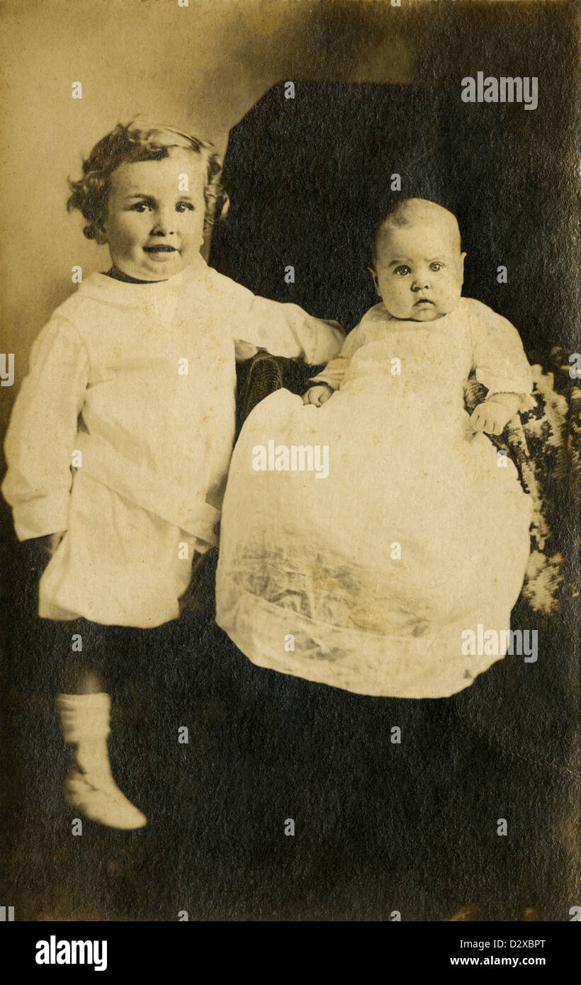 Circa 1910s photograph, toddler and his baby brother or sister in Edwardian dress. Stock Photo