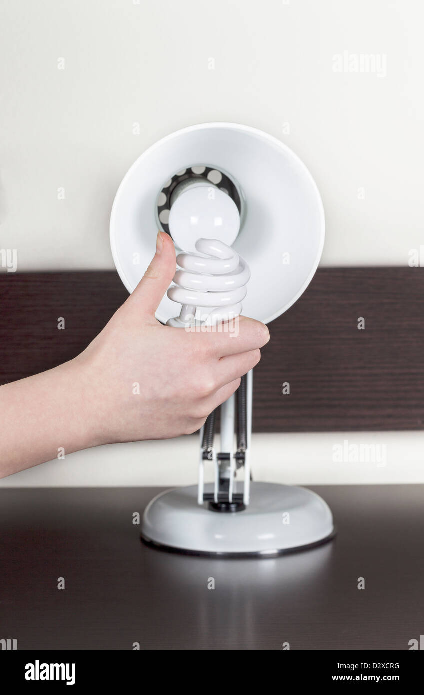 Vertical photo of female giving the thumbs up while hold energy efficient daylight bulb with old technology bulb in background Stock Photo