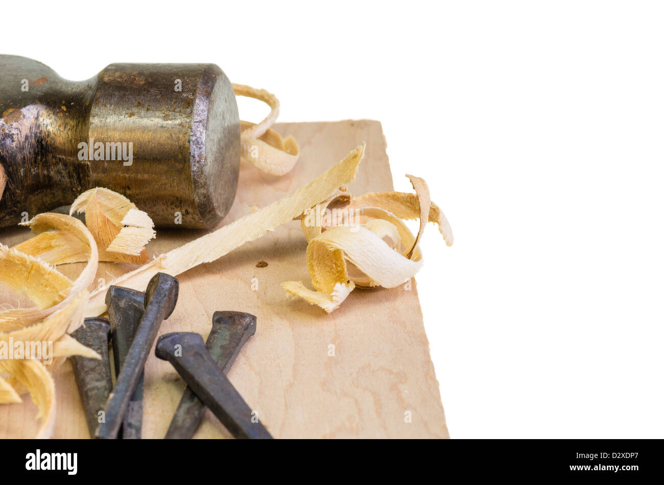 A hammer and nails on a wood board with sawdust shavings Stock Photo