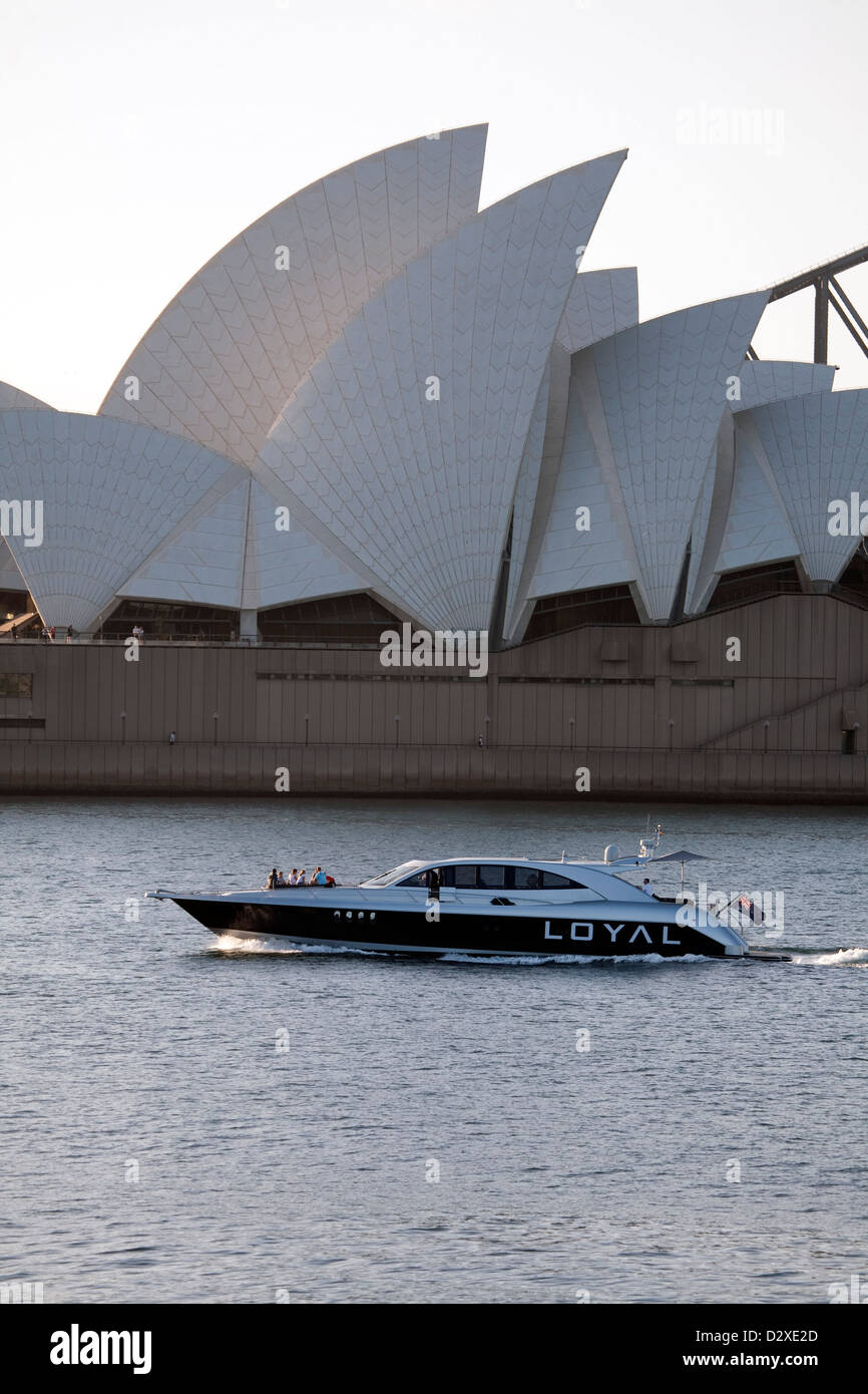 luxury motorboat cruising past the sails of the Sydney Opera House in the late afternoon Sydney Australia Stock Photo