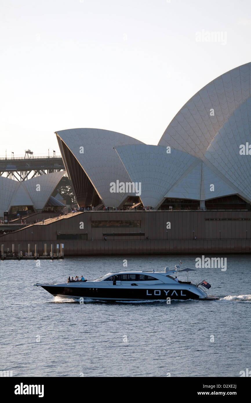Luxury charter motor cruiser passing thesails of the Sydney Opera House in the late afternoon Sydney Australia Stock Photo