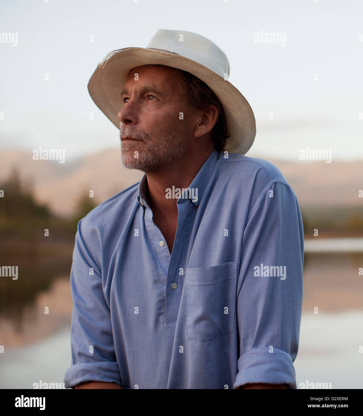 Close up of pensive man in hat at lakeside Stock Photo