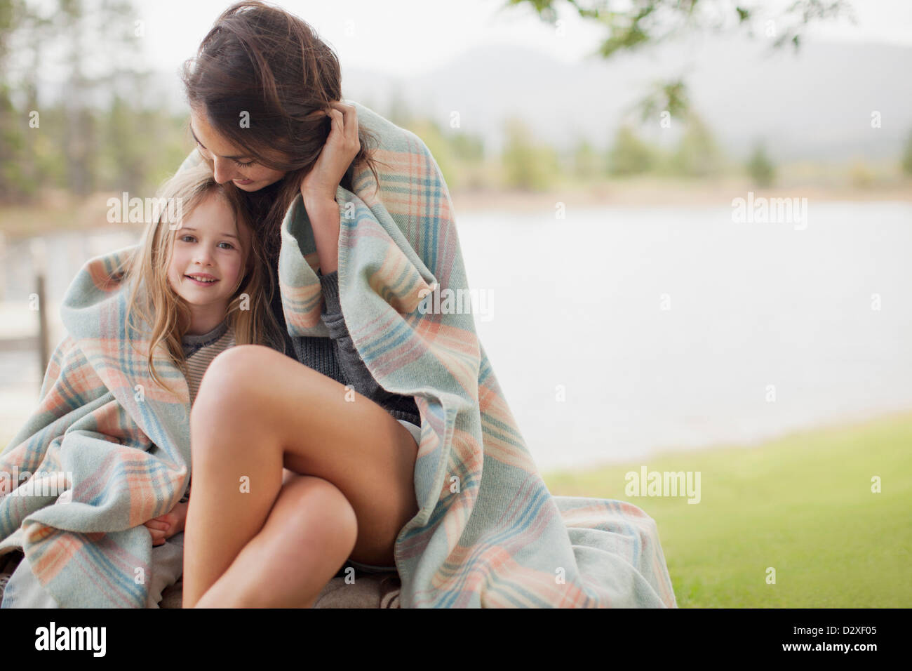 Portrait of smiling daughter wrapped in blanket with mother at lakeside Stock Photo Alamy