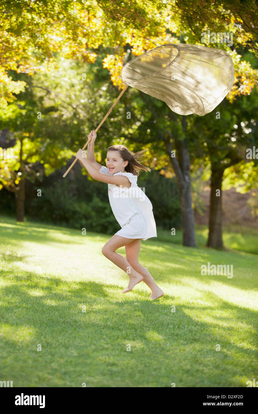 Happy girl running with butterfly net in grass Stock Photo - Alamy