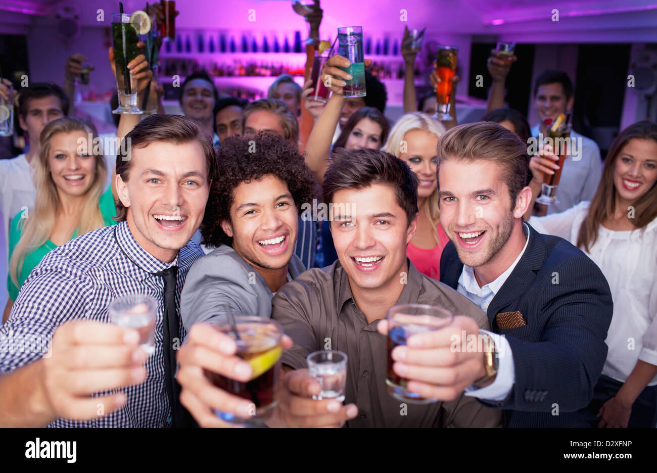 Portrait of enthusiastic crowd drinking cocktails in nightclub Stock Photo