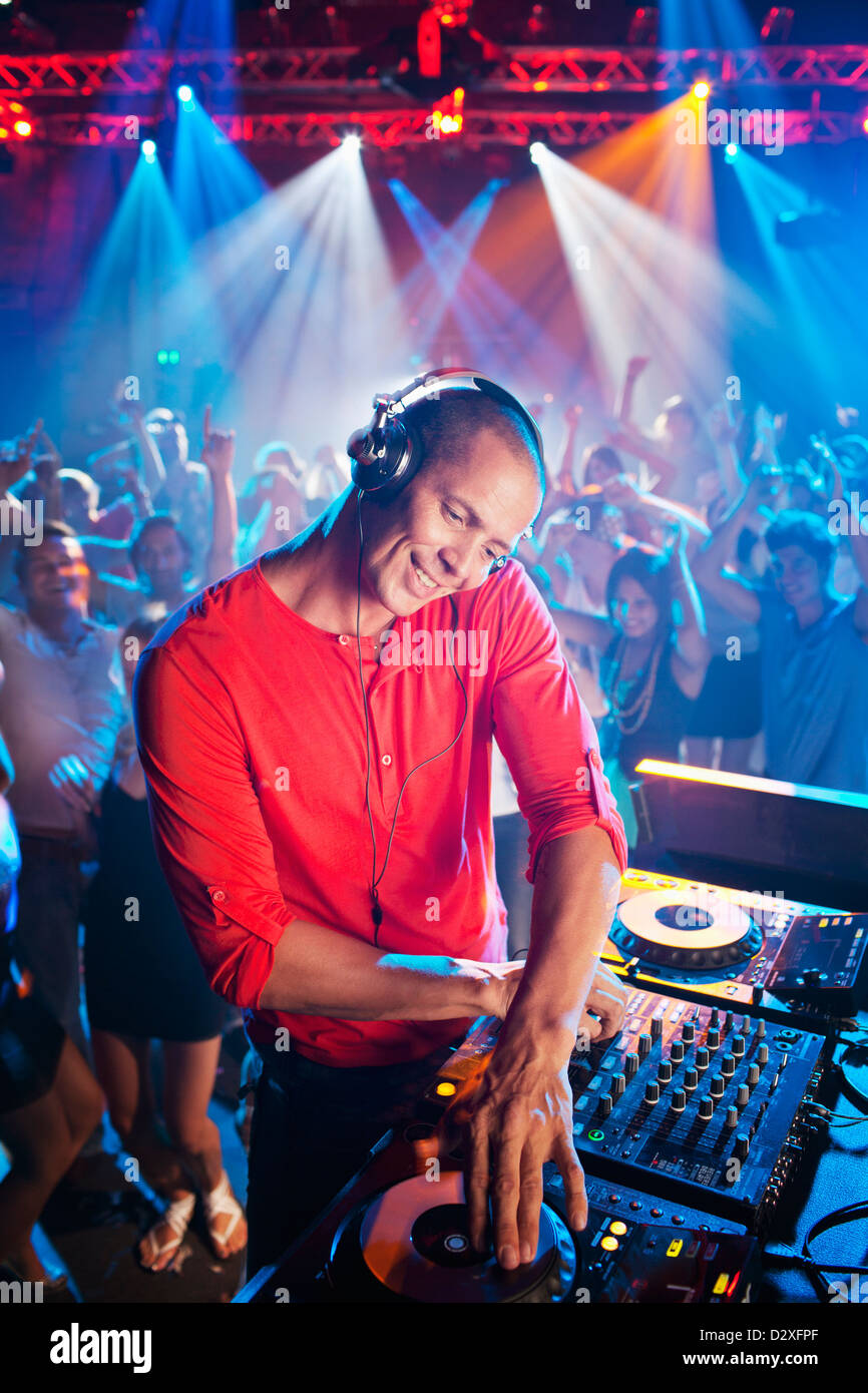 DJ at turntable with crowd on dance floor in background Stock Photo Alamy