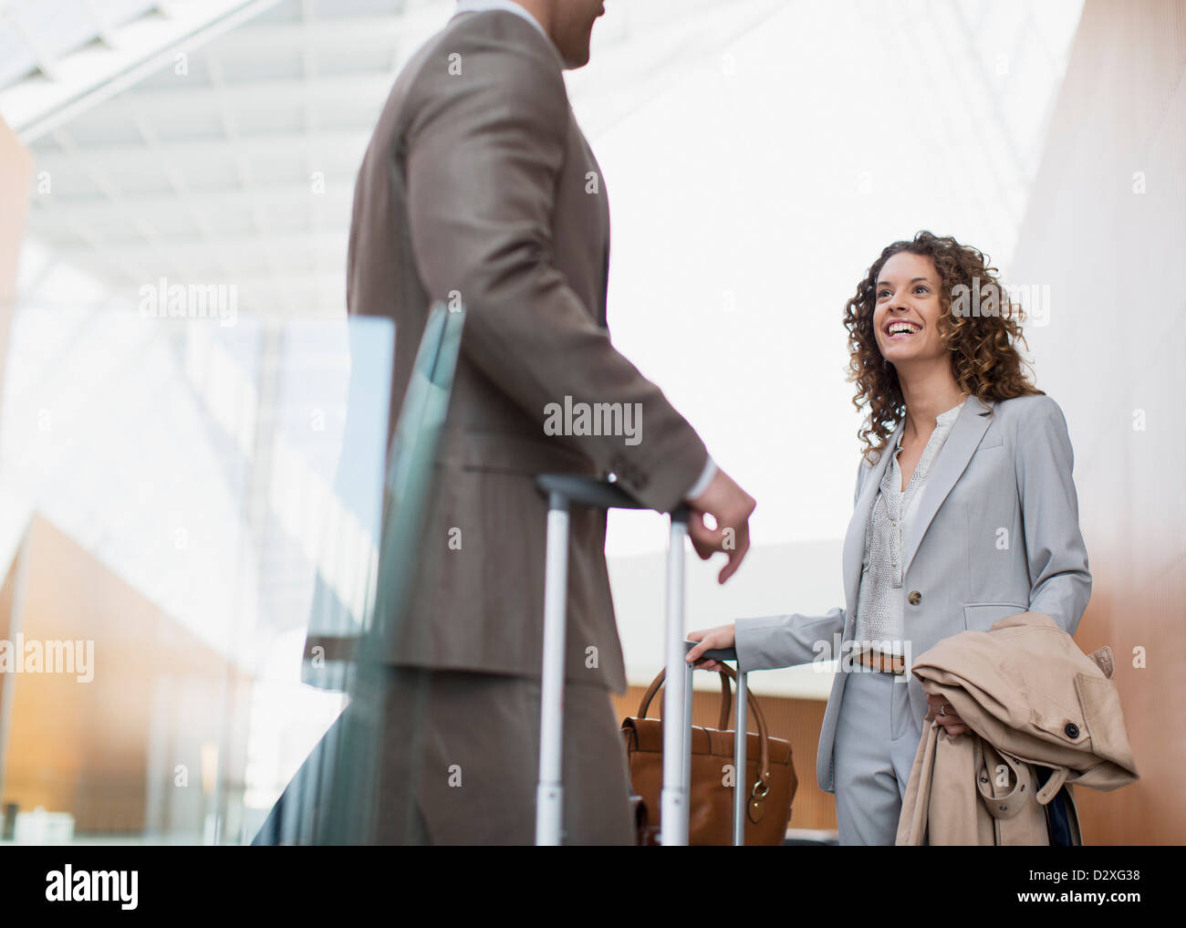 Smiling businesswoman talking to businessman in airport Stock Photo