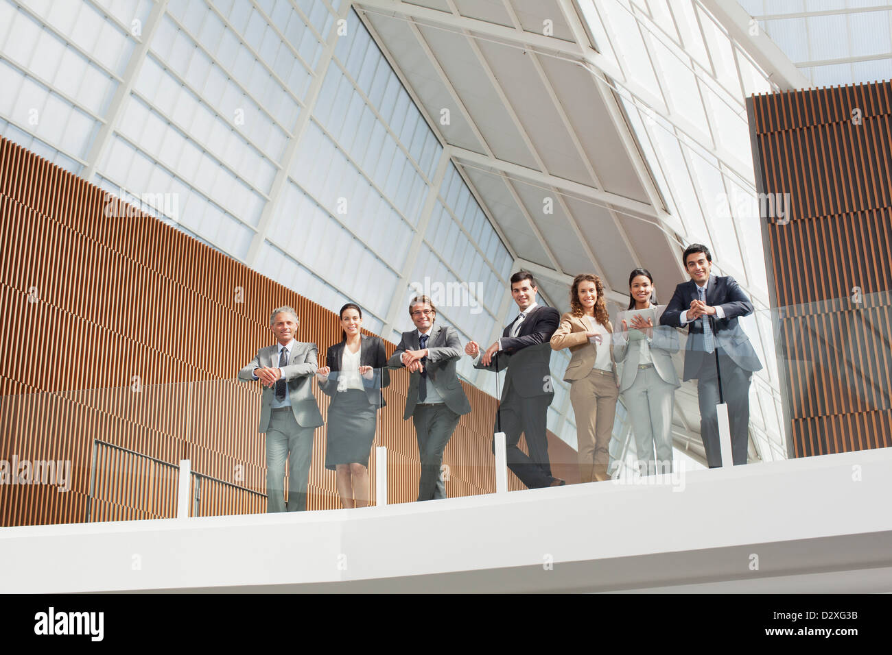 Portrait of smiling business people leaning on balcony railing Stock Photo