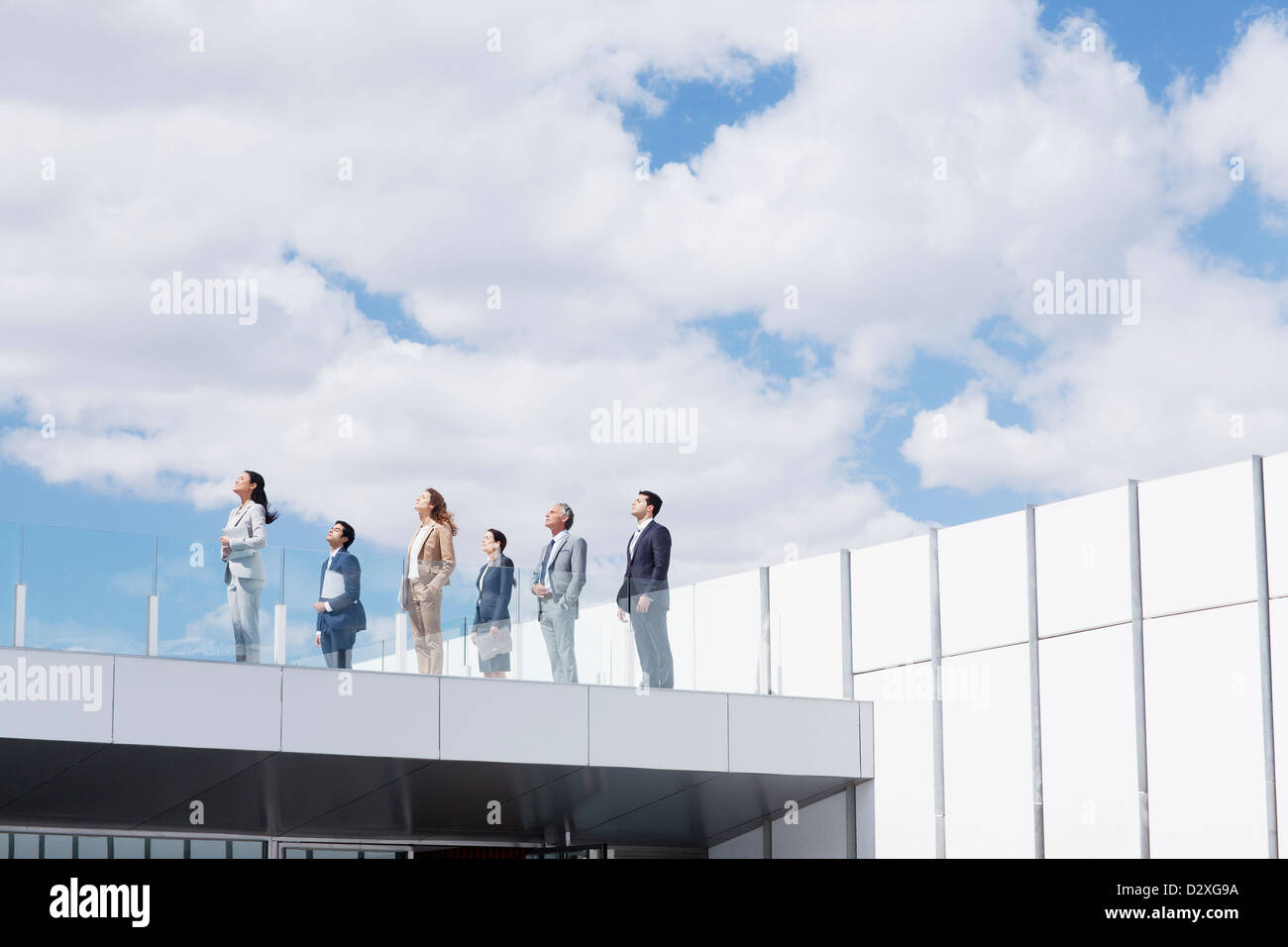 Business people on rooftop balcony looking up at sky Stock Photo