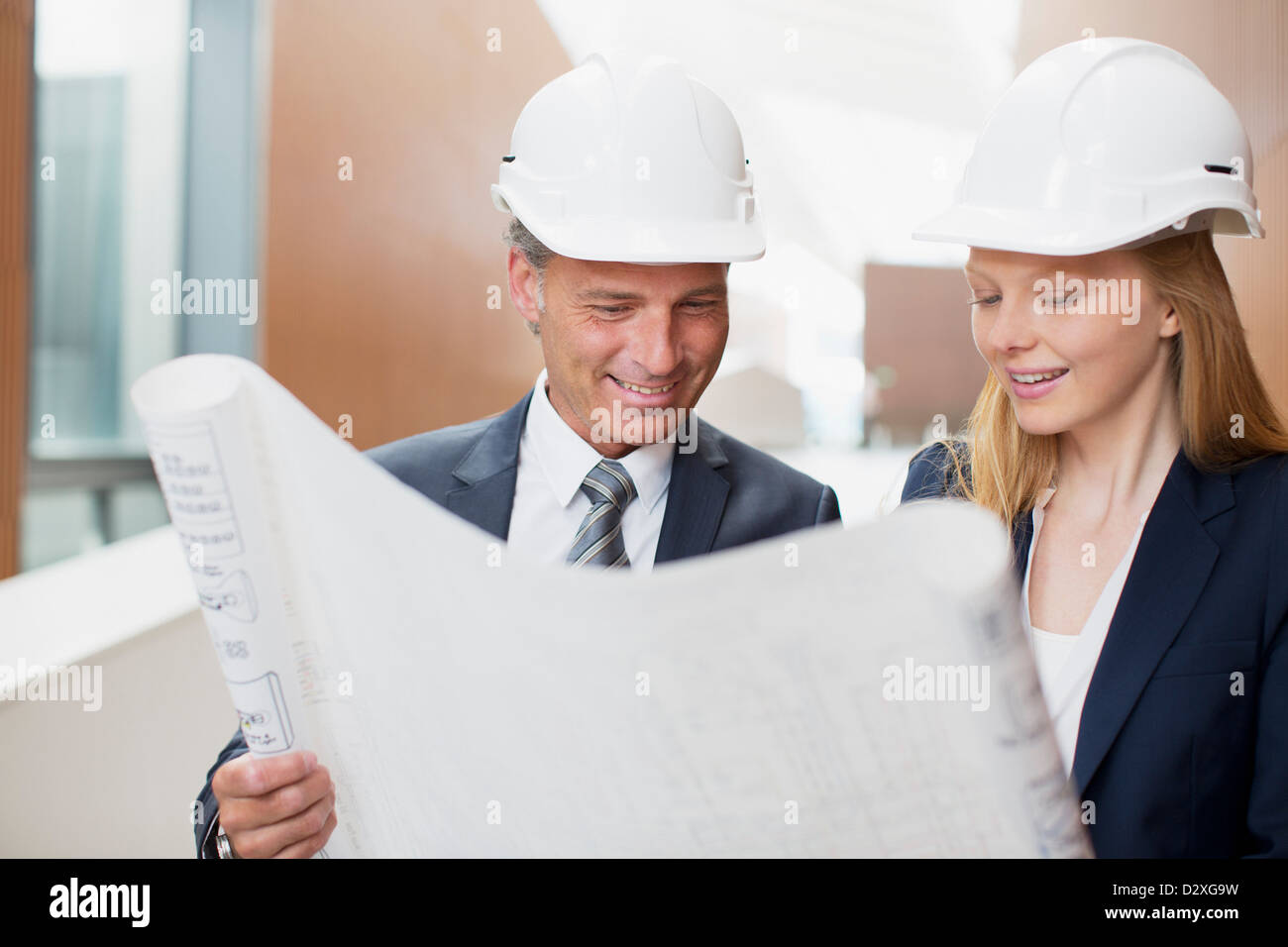 Architects wearing hard-hats and reviewing blueprints Stock Photo