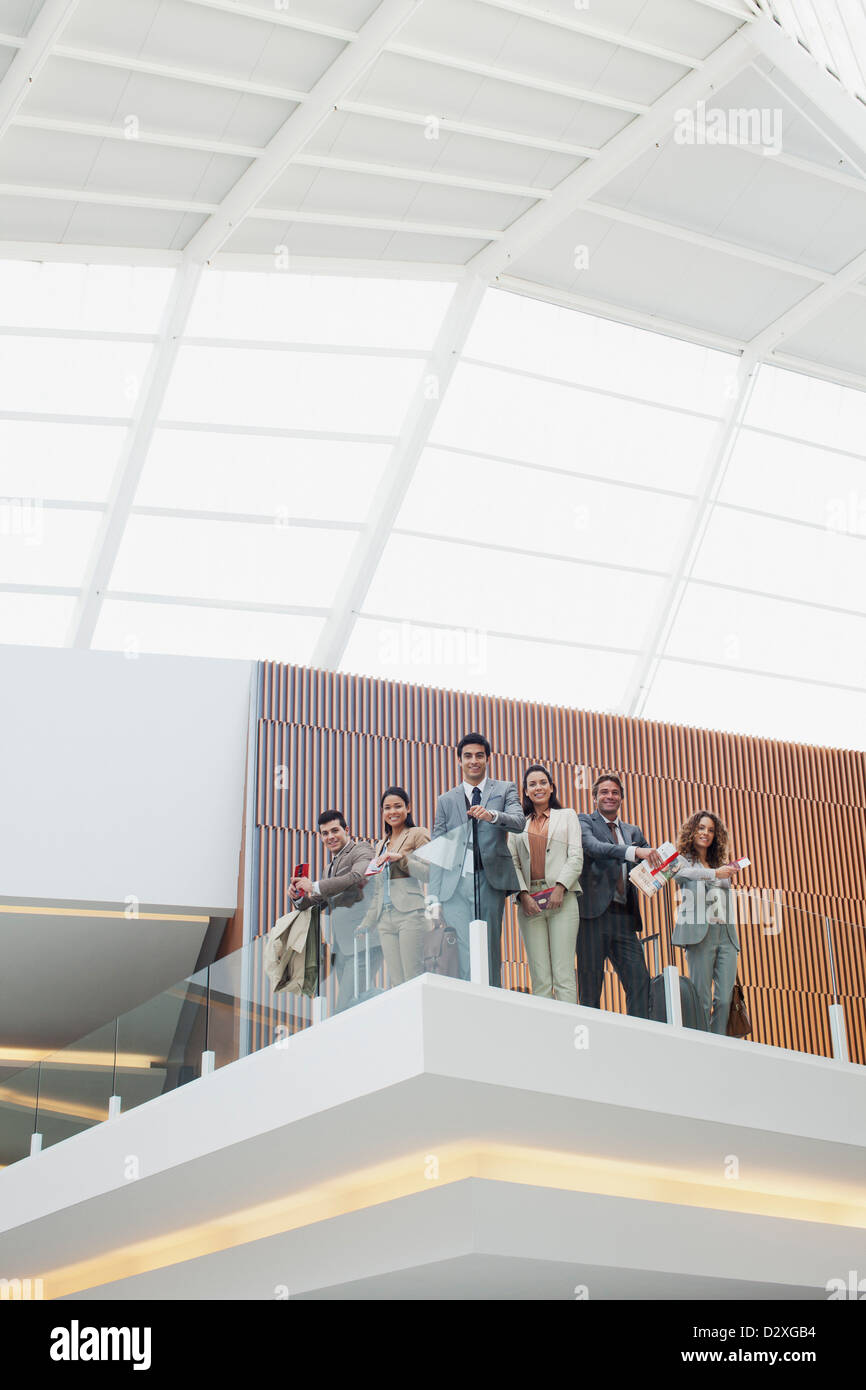 Portrait of smiling business people at glass railing of balcony in modern office Stock Photo