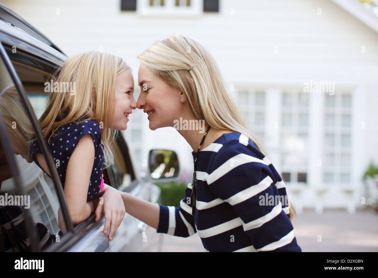 Mother and daughter touching noses in car Stock Photo