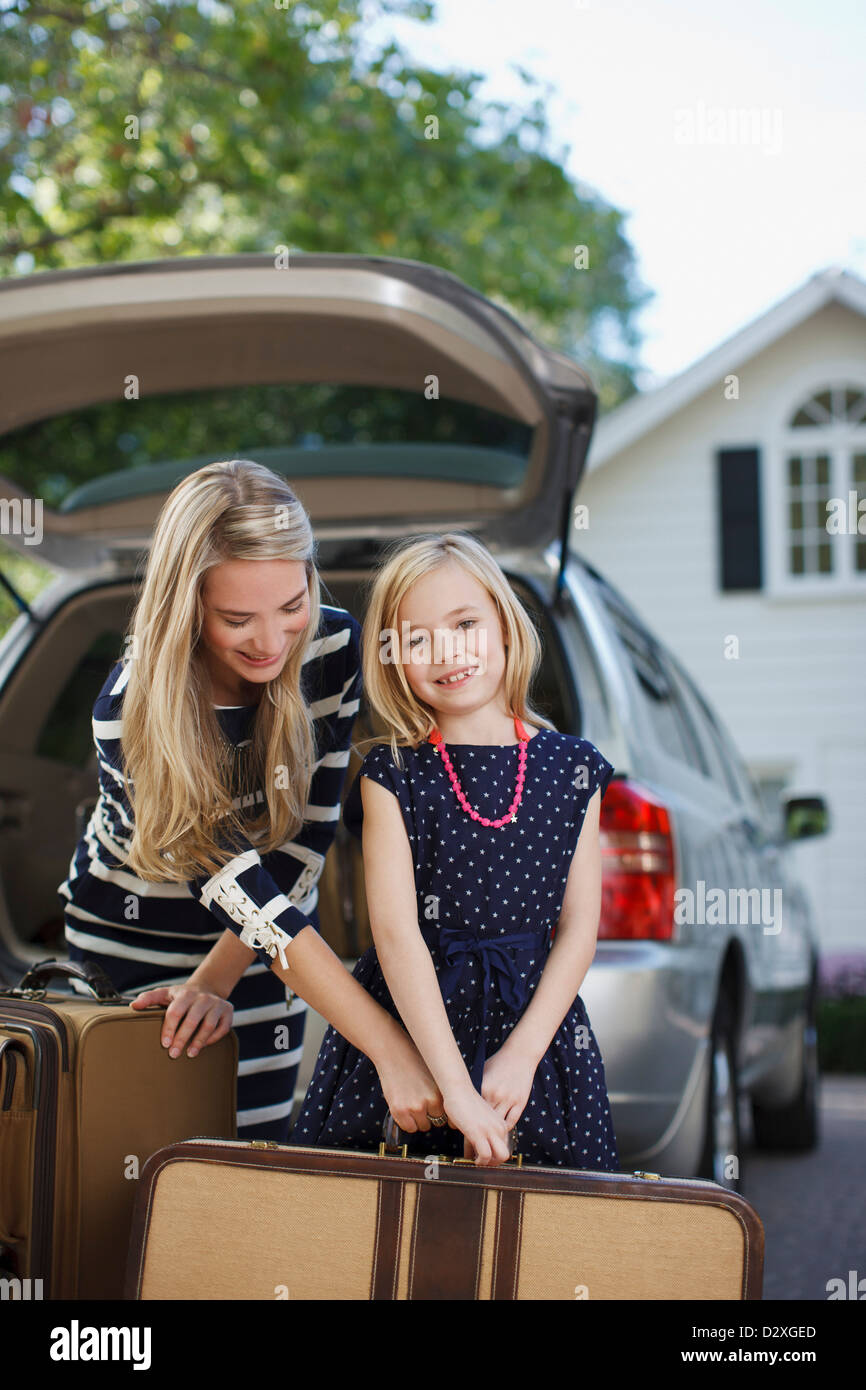 Mother and daughter carrying luggage to car Stock Photo