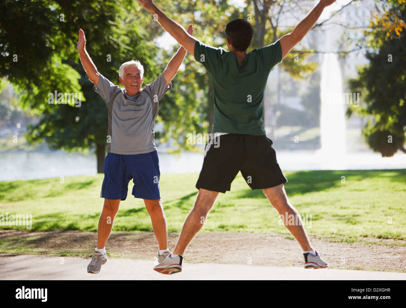 Older men doing jumping jacks outdoors Stock Photo