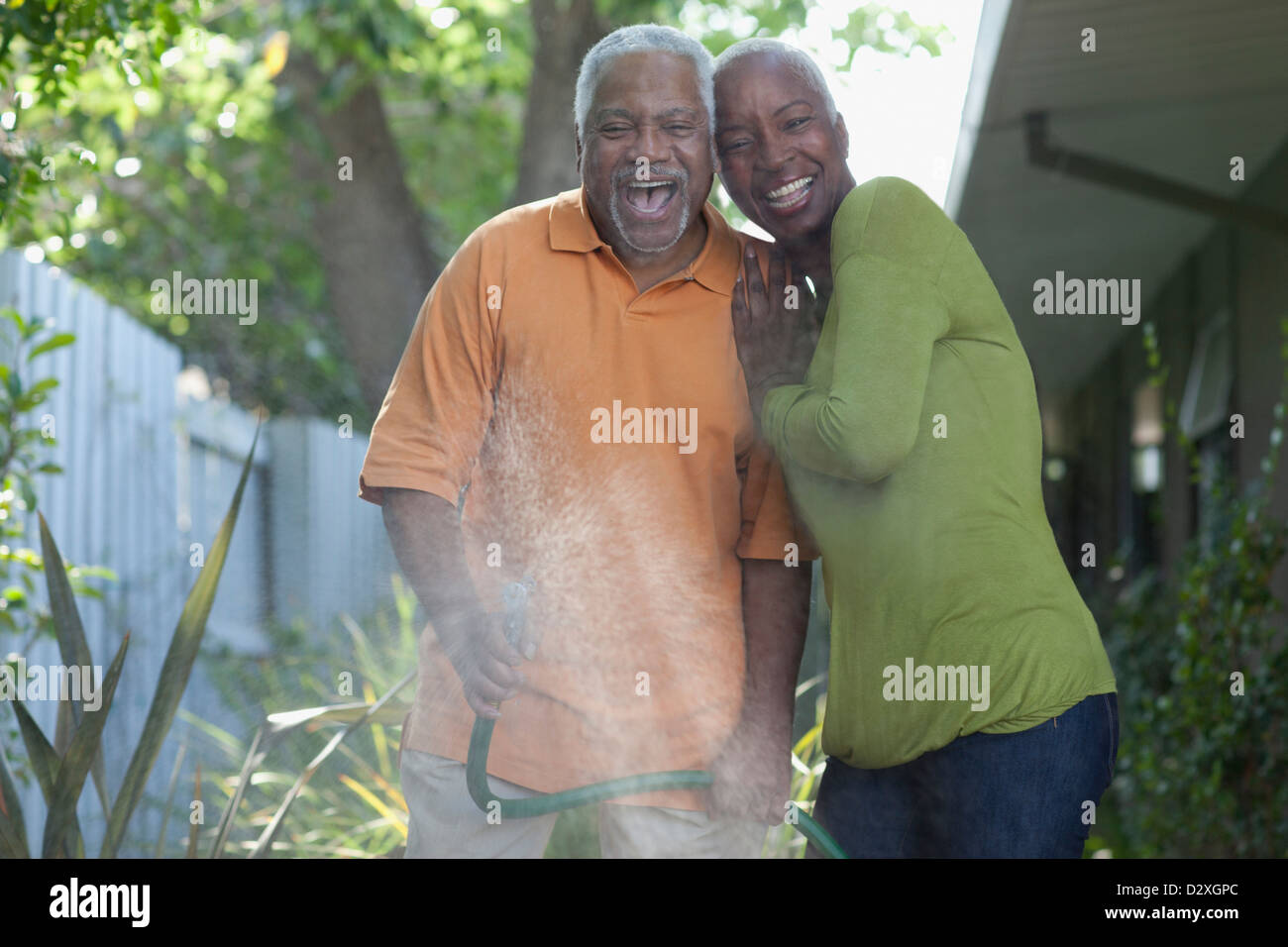 Older couple watering plants in backyard Stock Photo