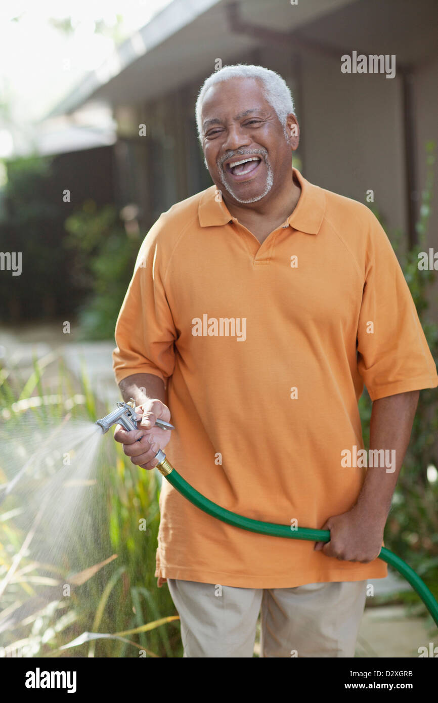 Older men watering plants in backyard Stock Photo