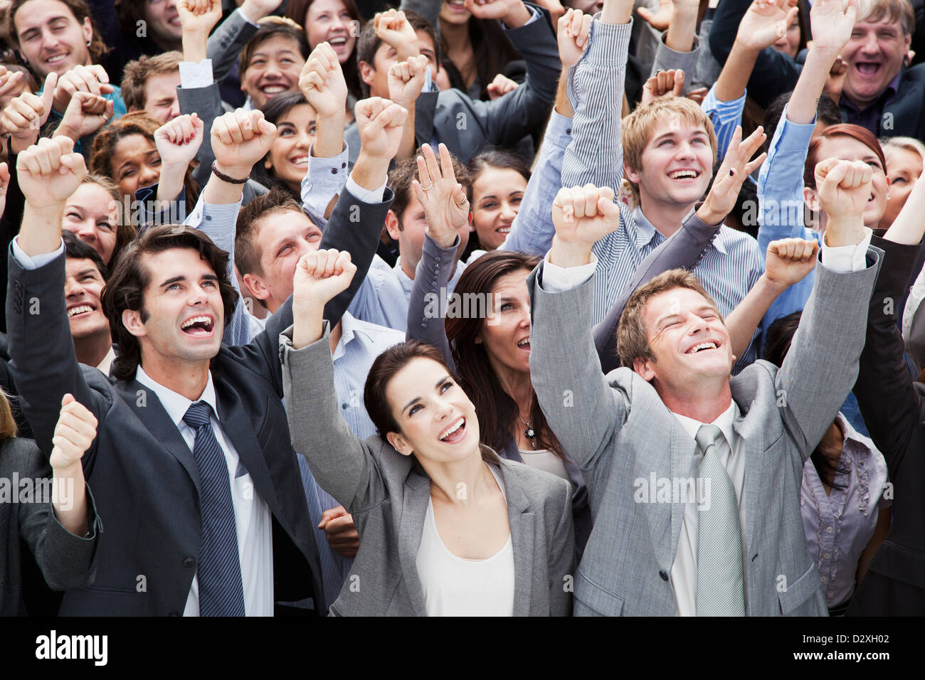 Smiling Crowd Of Business People Cheering With Arms Raised Stock Photo