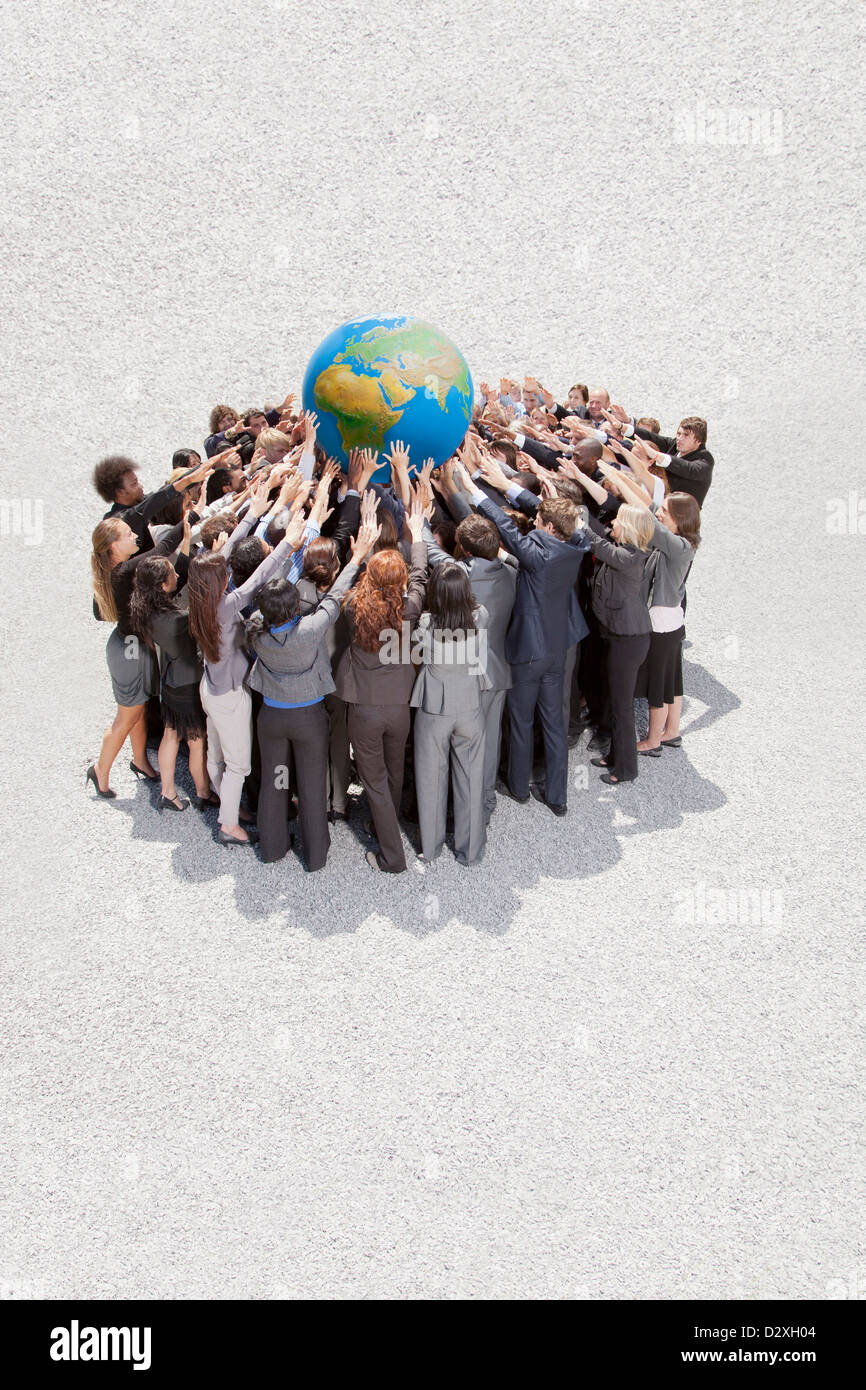Crowd of business people in huddle lifting globe overhead Stock Photo