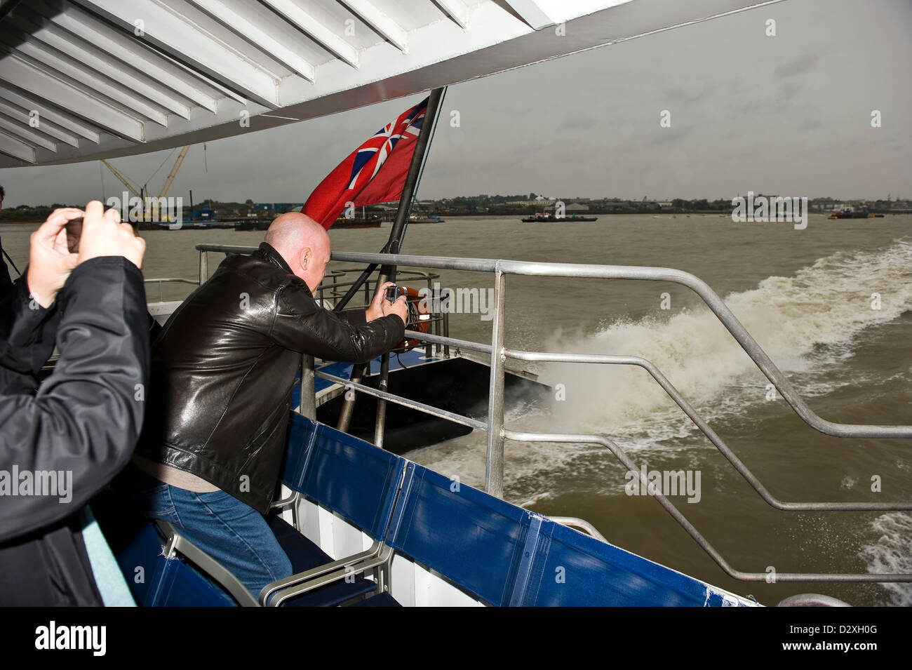 People taking photographs of London from the back of a River Thames Clipper on a wet Autumn day. Stock Photo