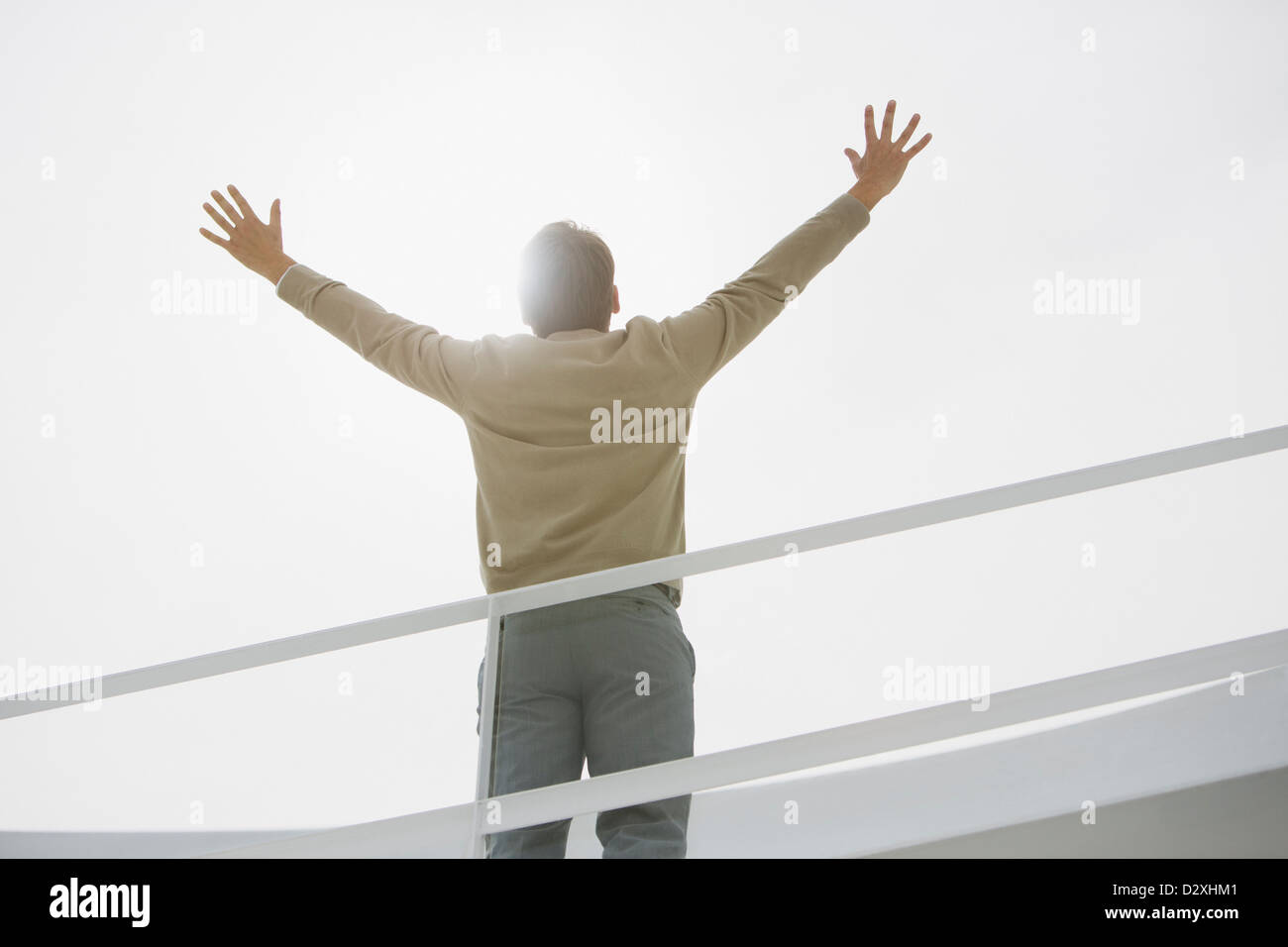 Sun shining behind businessman with arms raised Stock Photo