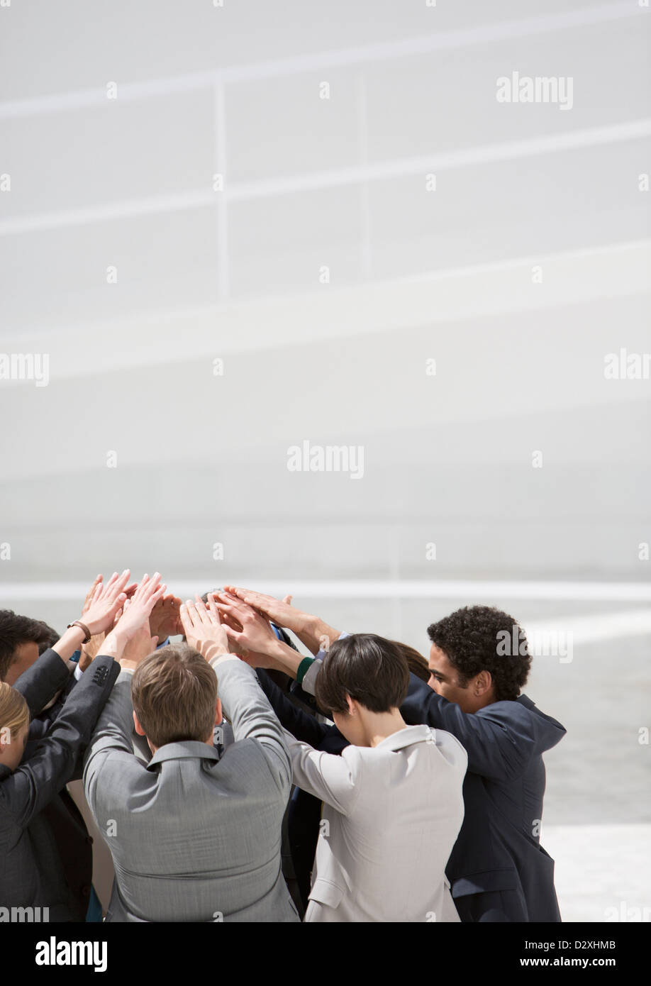 Business people with arms raised in huddle Stock Photo