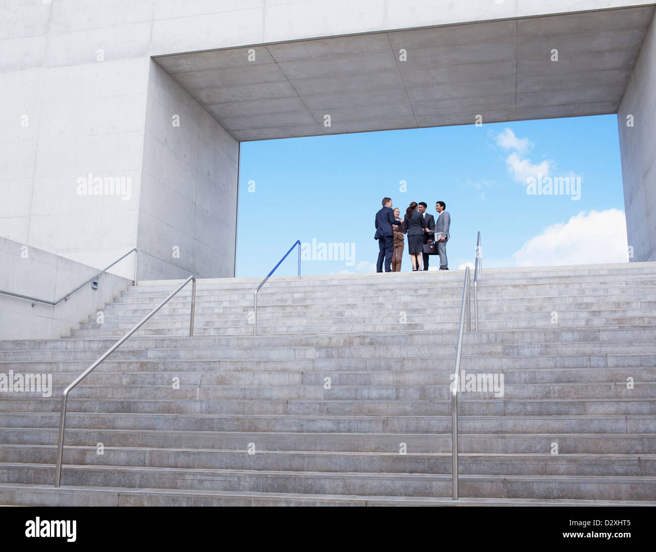 Business people meeting at top of urban stairs Stock Photo
