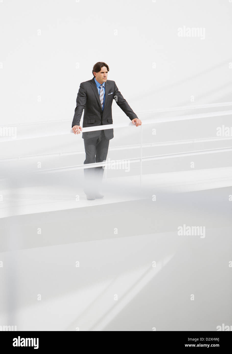 Businessman leaning on railing at elevated walkway Stock Photo