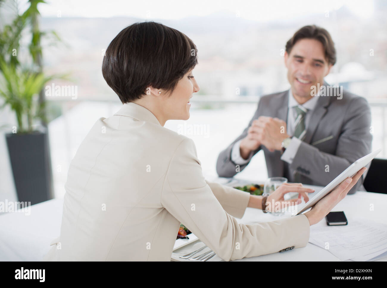 Businessman and businesswoman using digital tablet at restaurant table Stock Photo