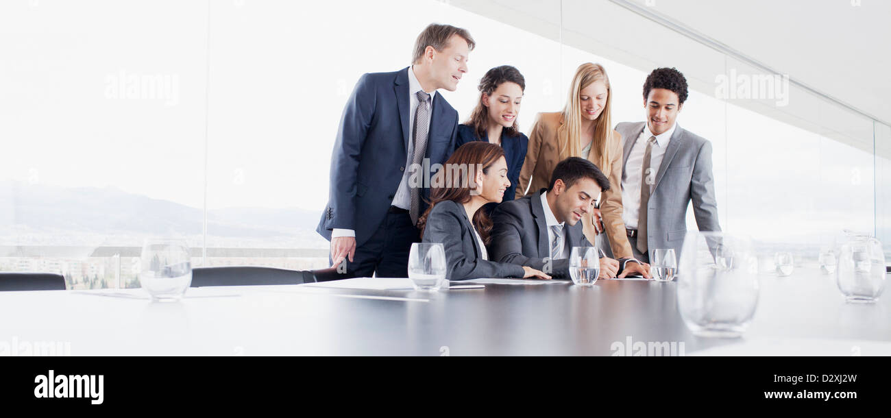 Business people watching businessman sign contract in conference room Stock Photo