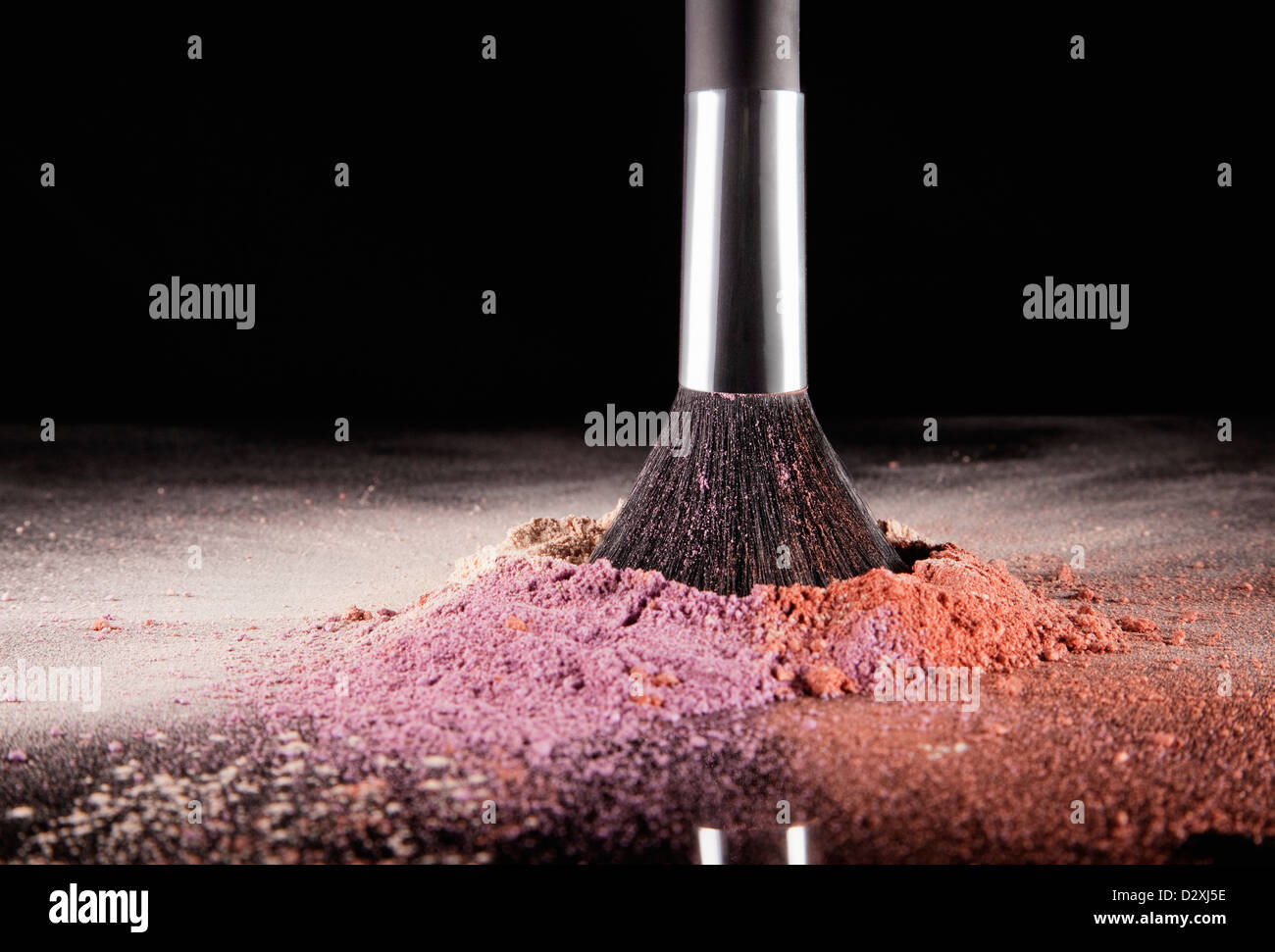 Makeup brush dipping into multicolor blush splatter Stock Photo