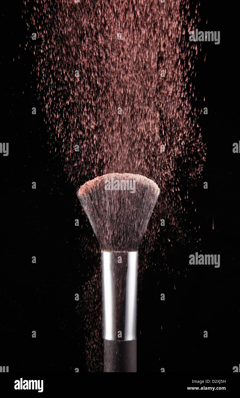 Blush powder blowing from makeup brush Stock Photo