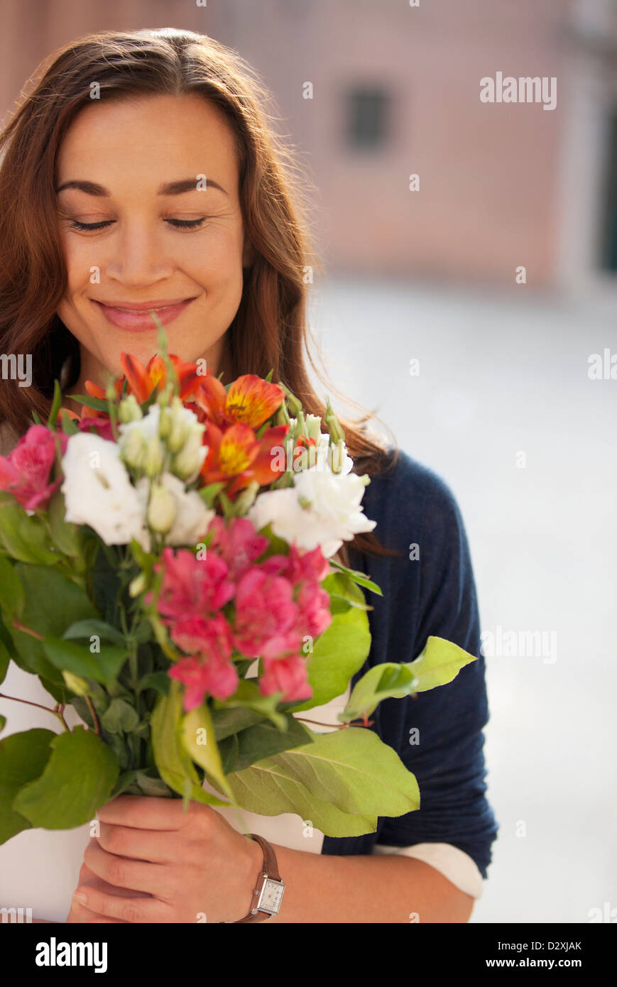 Smiling woman smelling bouquet of flowers Stock Photo