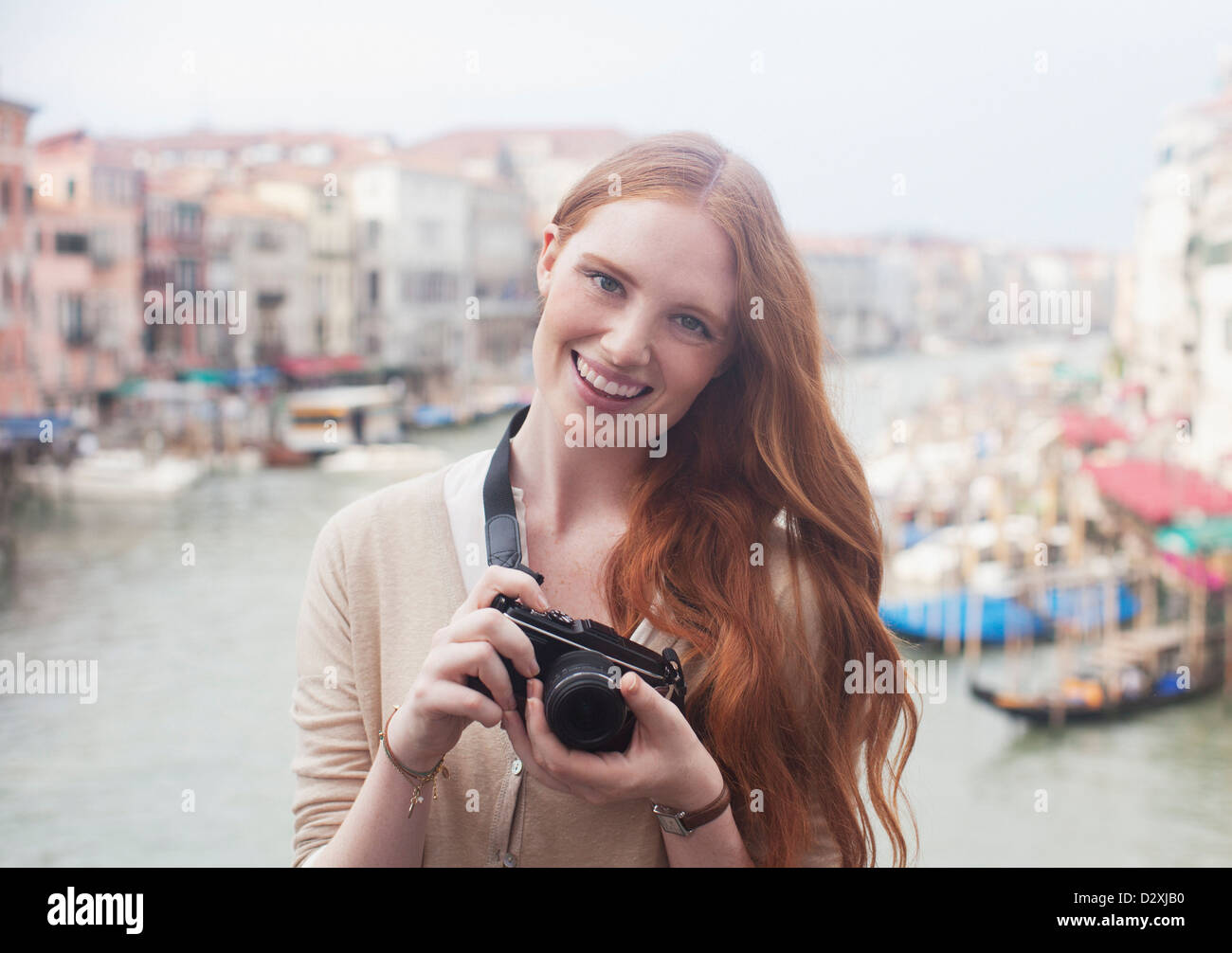 Portrait of smiling woman holding digital camera at waterfront in ...