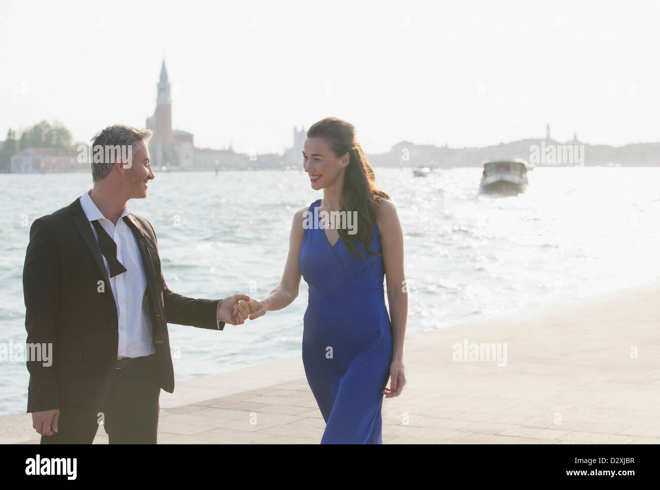 Well-dressed couple holding hands at waterfront in Venice Stock Photo