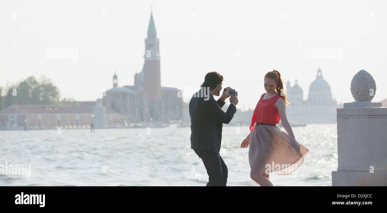 Man filming woman at waterfront in Venice Stock Photo