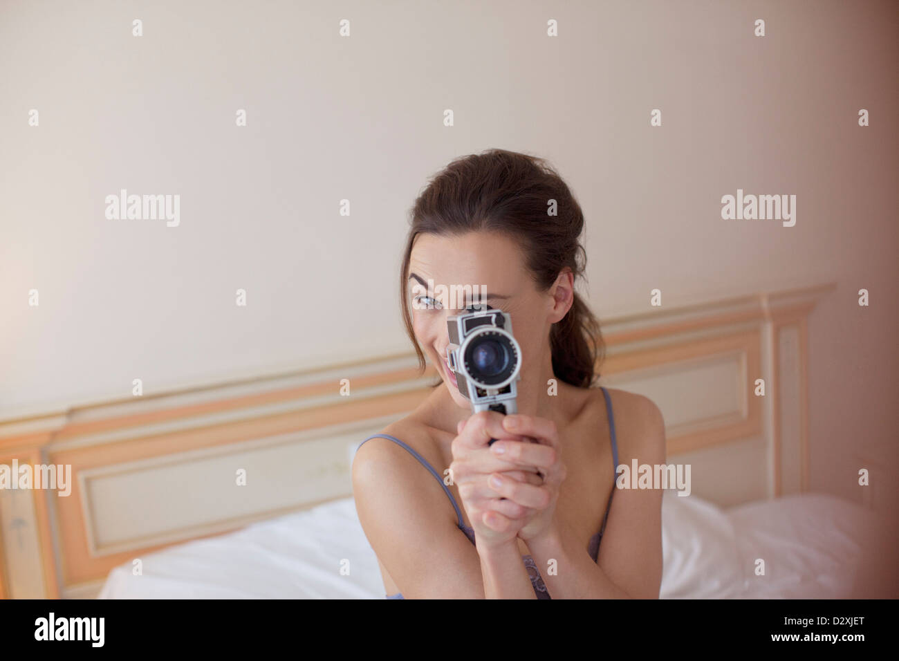 Portrait of woman holding old-fashioned video camera in bed Stock Photo