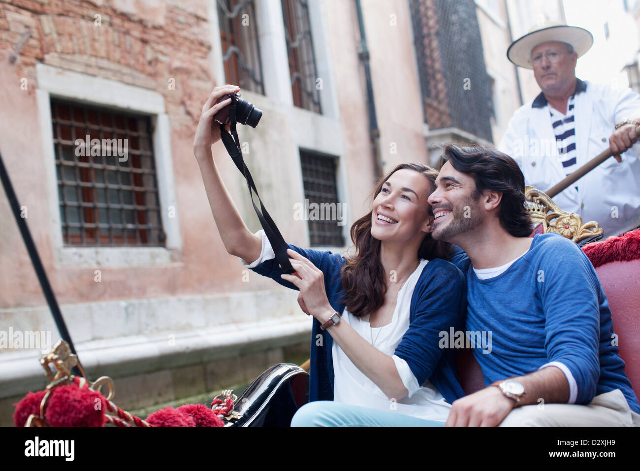 Smiling couple taking self-portrait with digital camera in gondola on canal in Venice Stock Photo