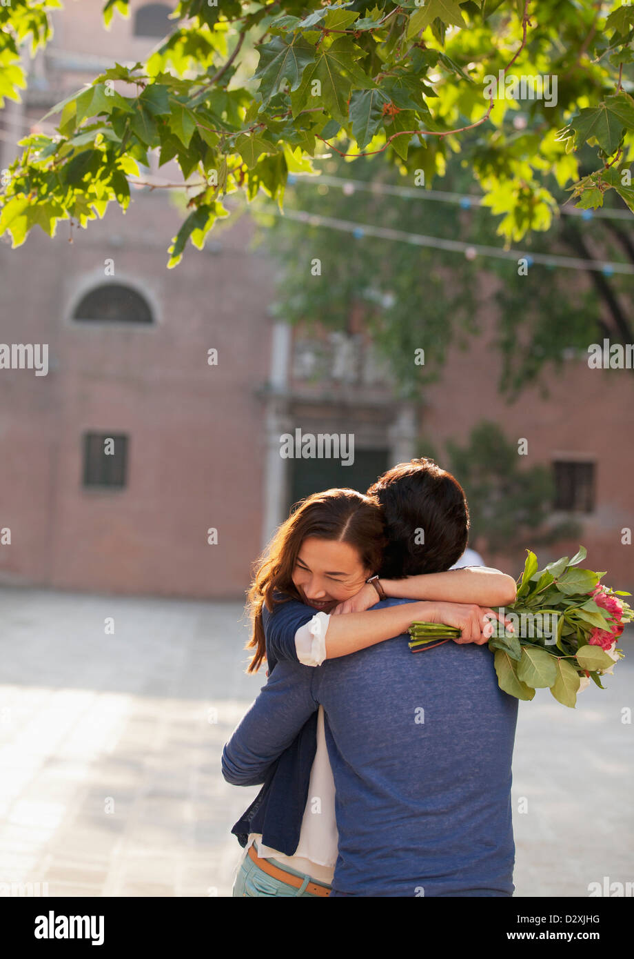 Woman holding flowers and hugging man Stock Photo