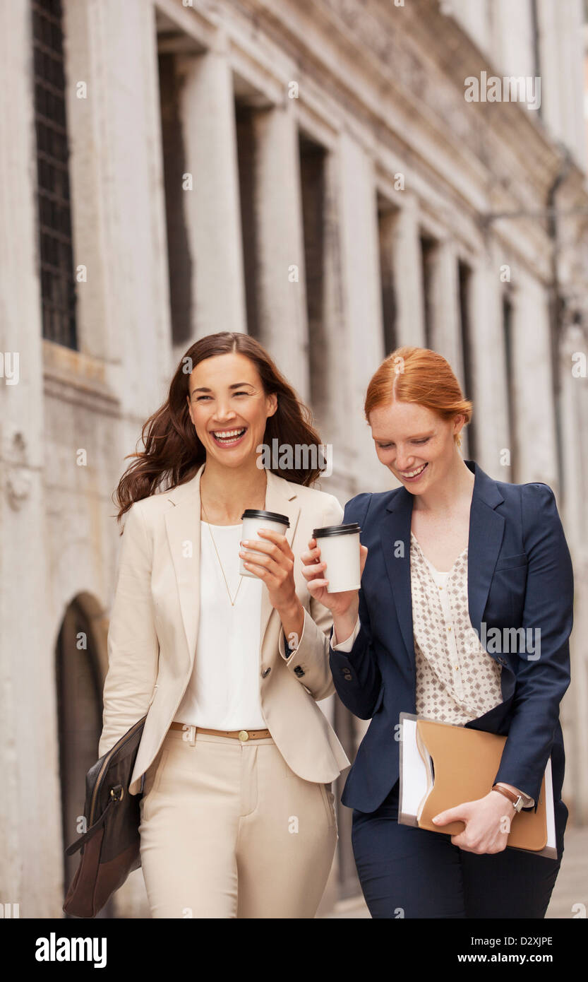 Smiling women walking with coffee Stock Photo Alamy