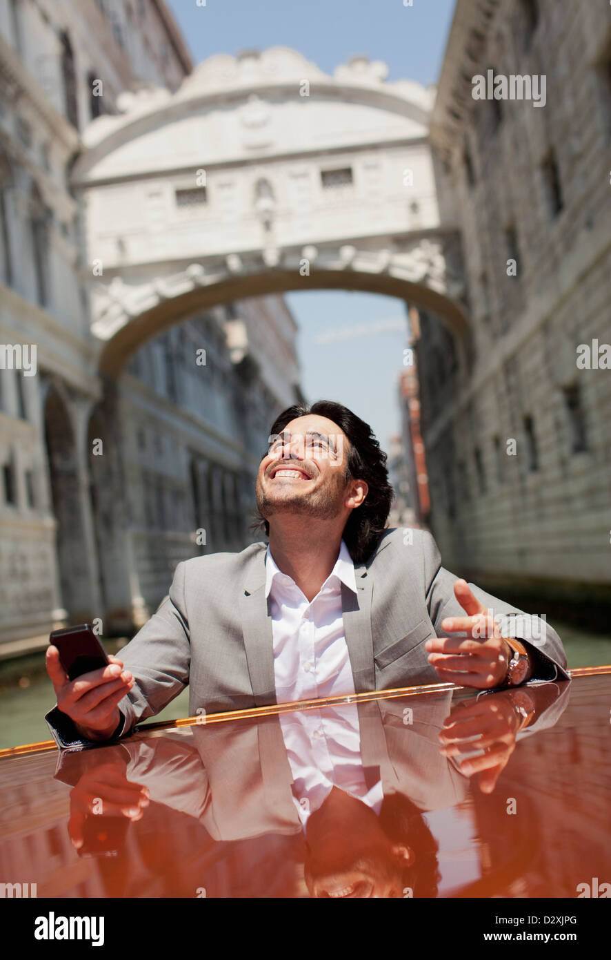 Enthusiastic businessman riding on boat through canal in Venice Stock Photo