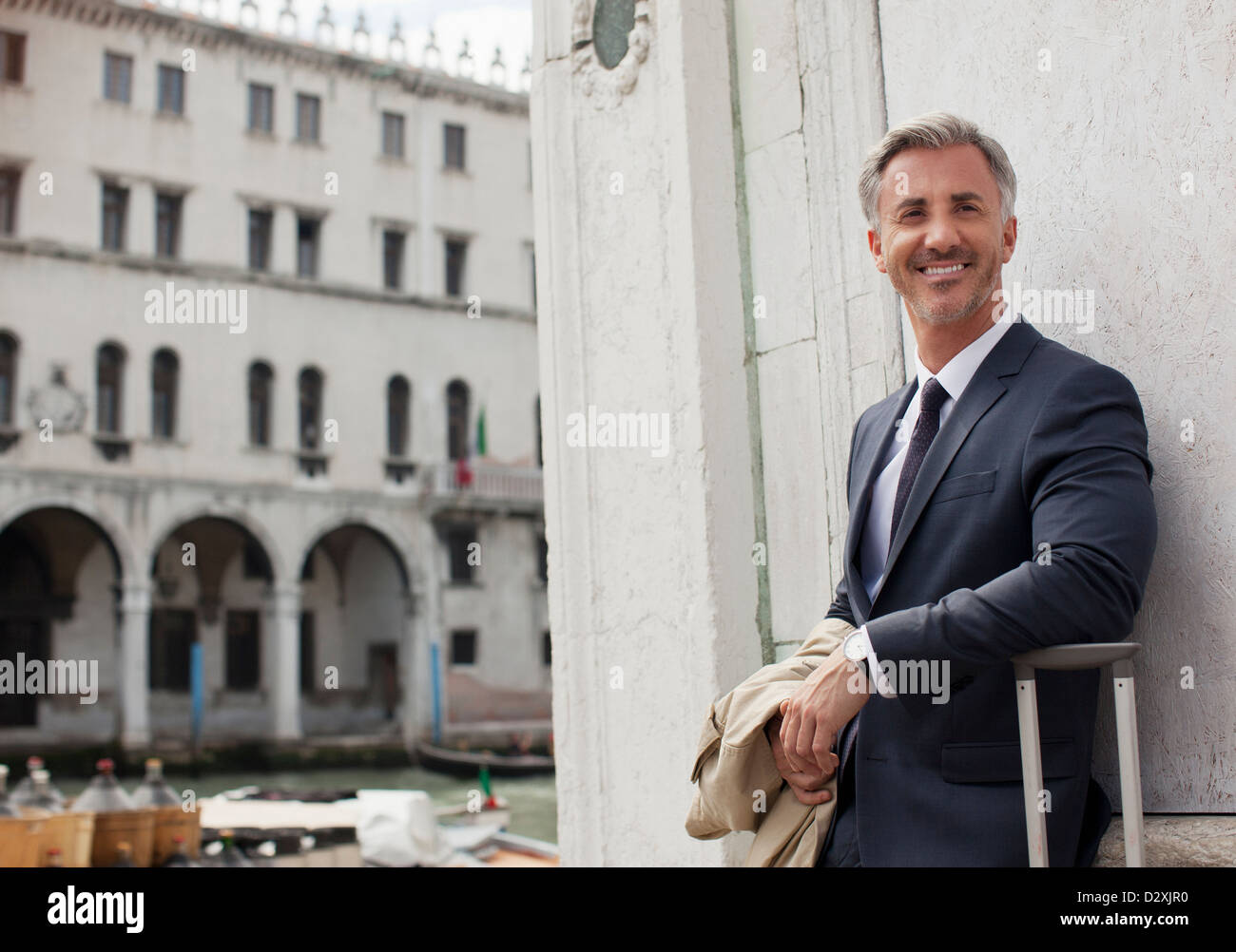 Portrait of smiling businessman with suitcase in Venice Stock Photo