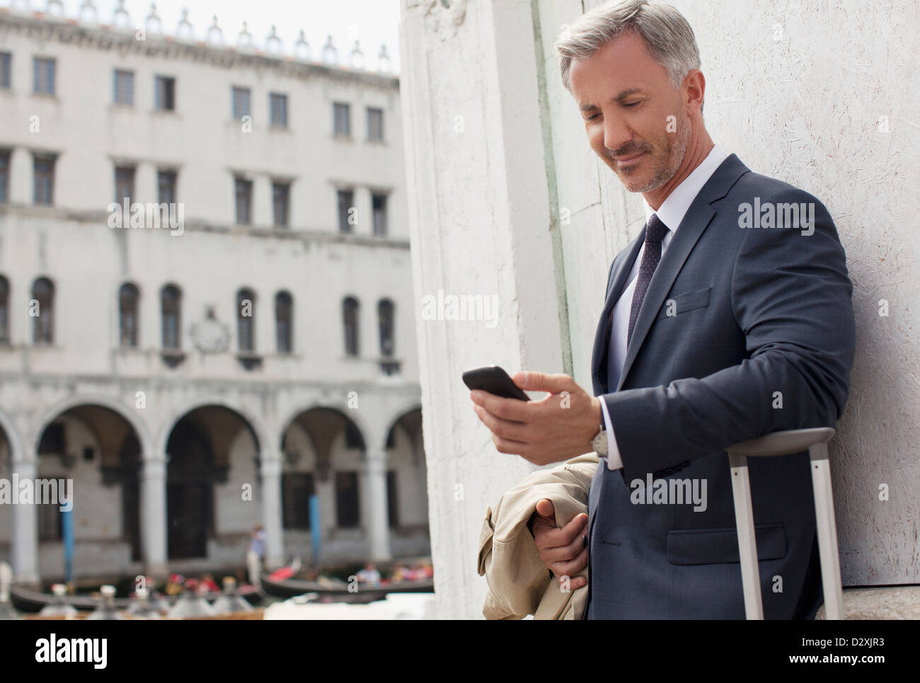 Businessman looking down at cell phone in Venice Stock Photo