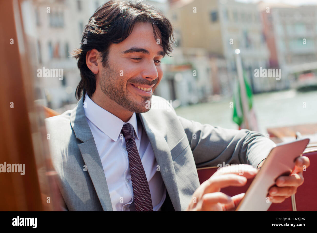Smiling businessman using digital tablet on boat in Venice Stock Photo