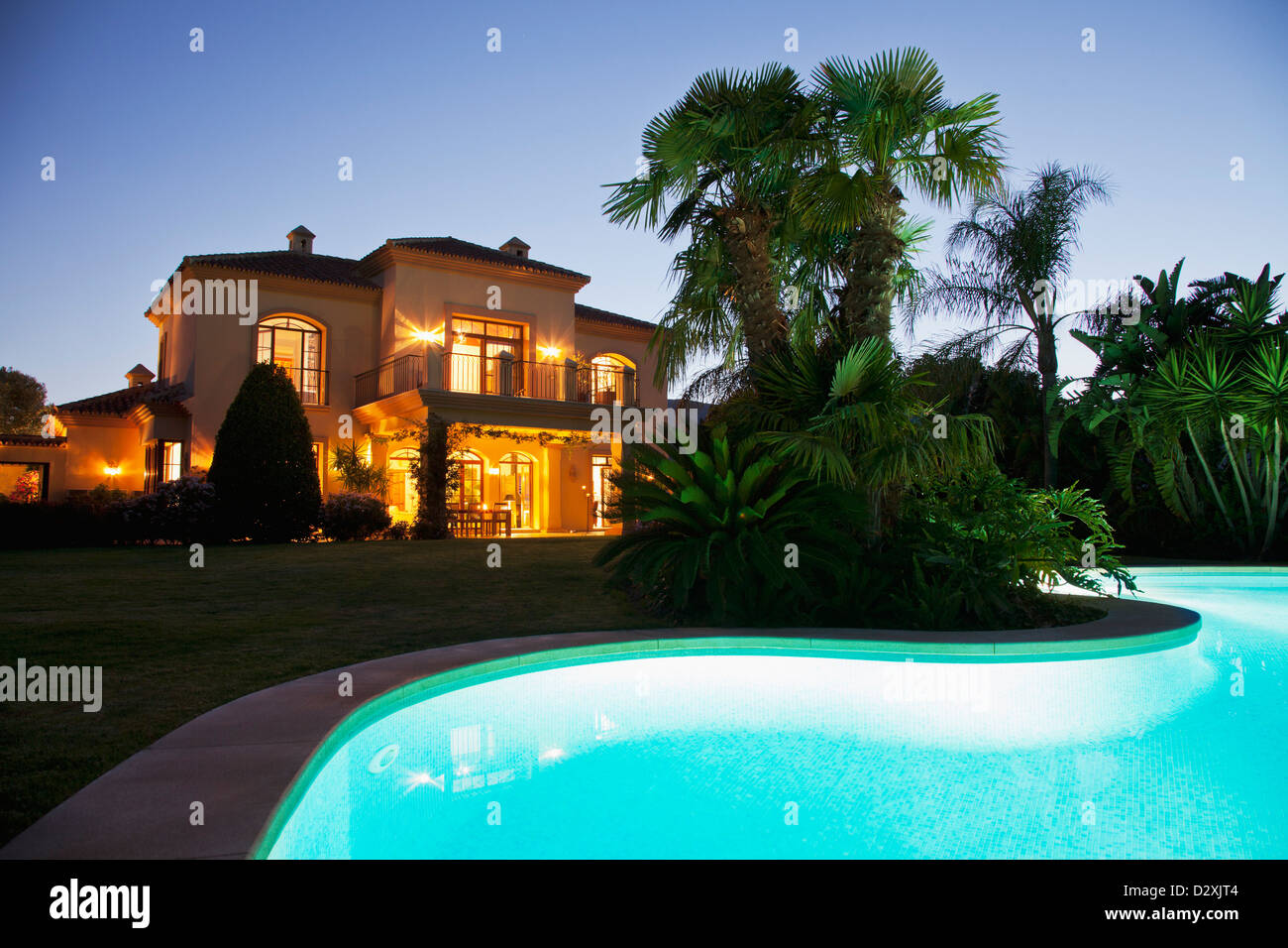 Luxury swimming pool and villa illuminated at night Stock Photo