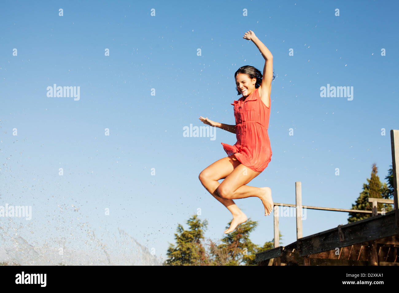 Smiling woman jumping off dock Stock Photo