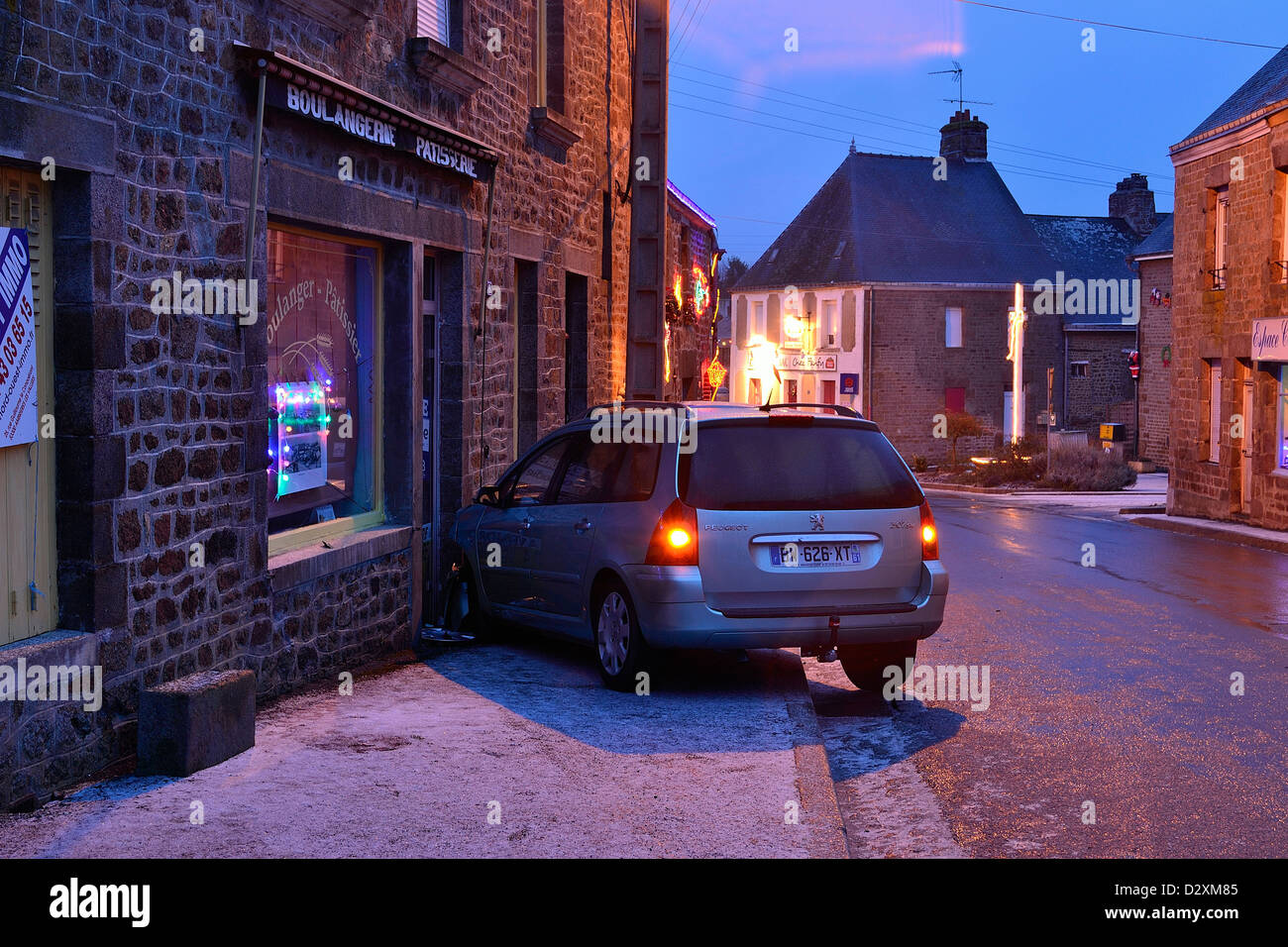 Skid of a car on the icy road, the car finish its race on a house of the village, in winter. Stock Photo